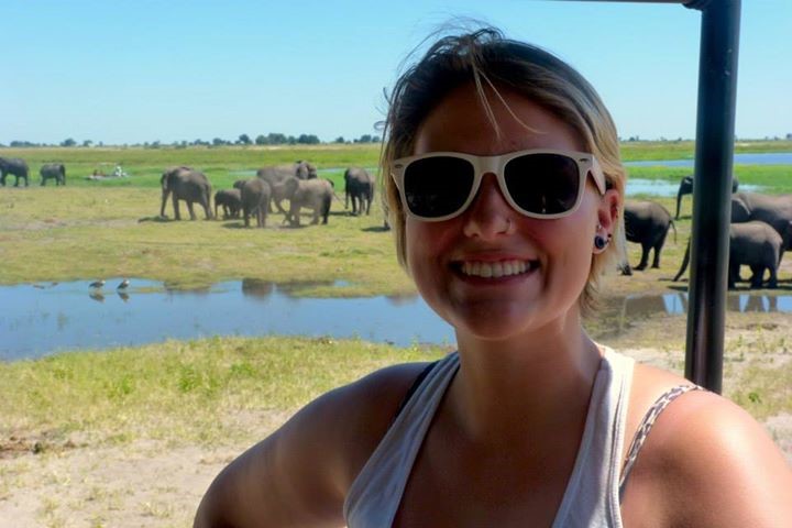 Student poses with elephants in background